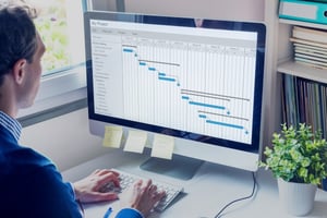 A man looks at a project timeline in a spreadsheet, a sign his client onboarding process could use an upgrade.